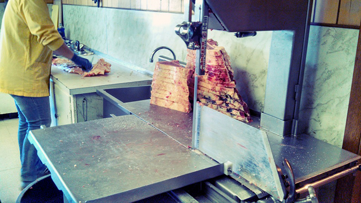 The half carcasses are split up even more and a band saw is used to cut the meat into even slices.